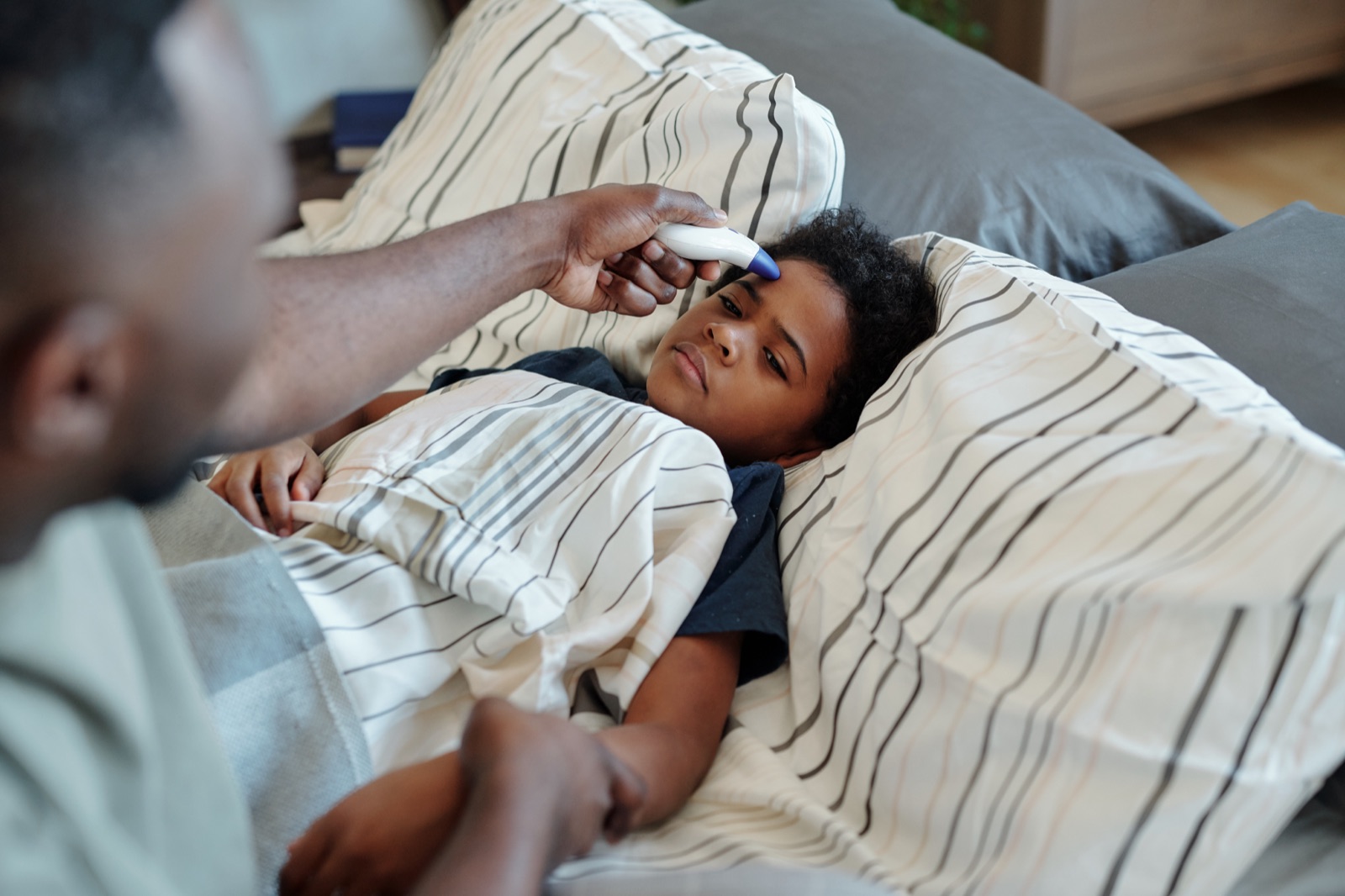 Parent checking a sick child’s temperature before calling A+ Pediatrics in Irvine, Kentucky