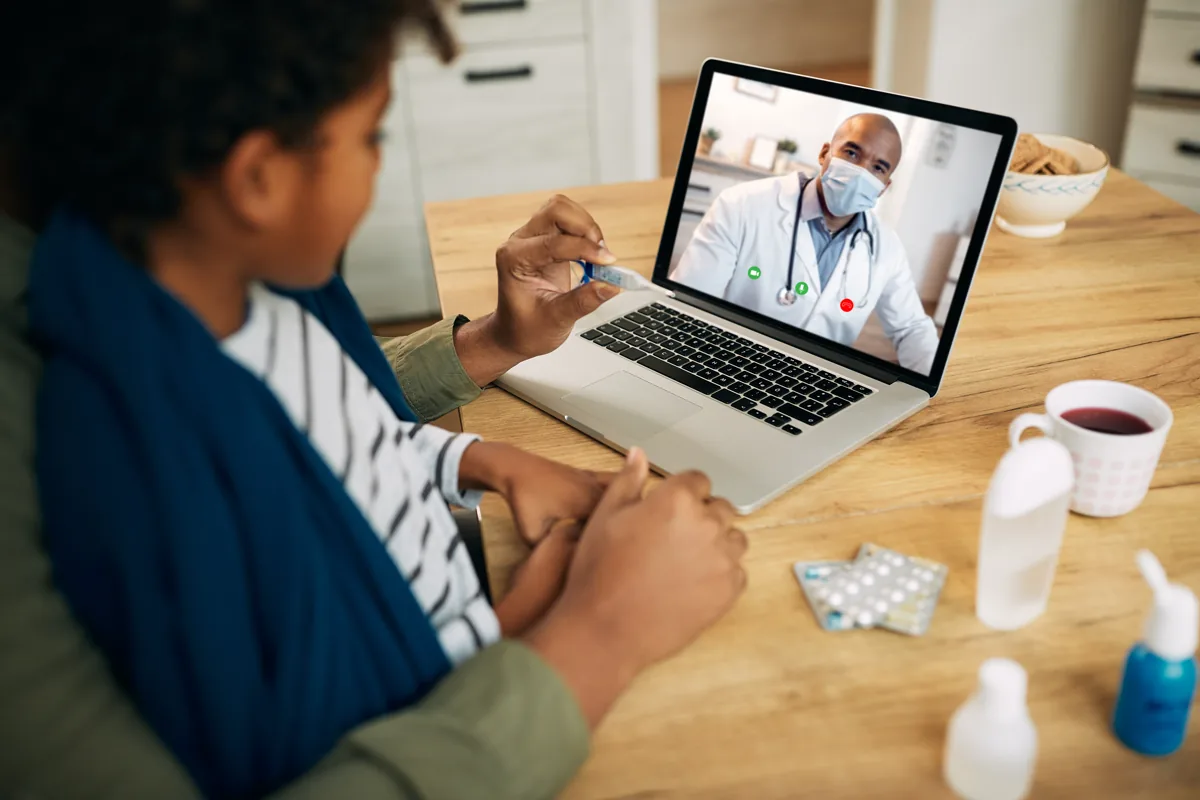 Parent and child sitting at home with a laptop nearby for a pediatric telehealth visit.